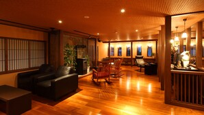 A spacious room with a wooden floor, a sofa, a rocking chair, and a small table. - Kusatsu Onsen Ryokan Yoshinoya (Kusatsu)