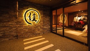 A stone wall with illuminated signage, a reception area with a glass partition, and a floral display. - Kusatsu Onsen Ryokan Yoshinoya (Kusatsu)