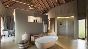 A modern bathroom with a freestanding bathtub, a vanity, and a shower area. - Mhondoro Safari Lodge & Villa (Vaalwater)