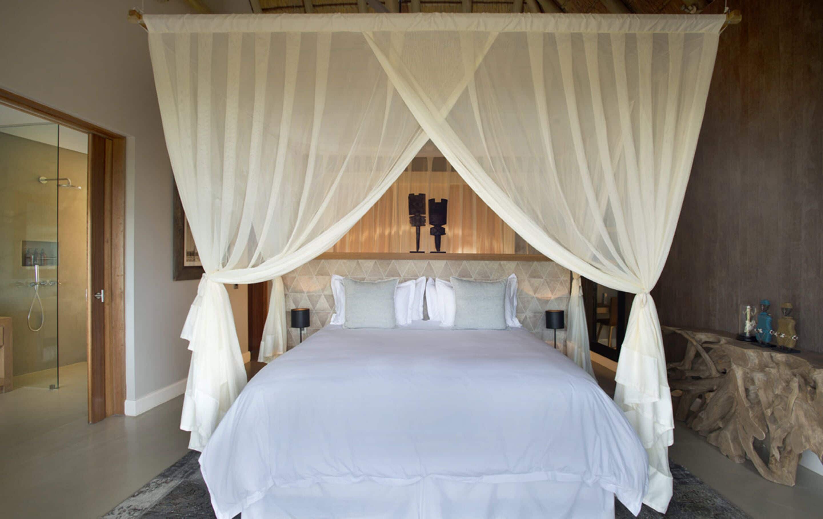 Un dormitorio con cama con dosel, puerta de ducha de vidrio y cabecera de madera.