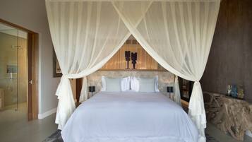 Un dormitorio con cama con dosel, puerta de ducha de vidrio y cabecera de madera.
