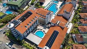 A hotel with multiple swimming pools, a rooftop with solar panels, and a central courtyard.