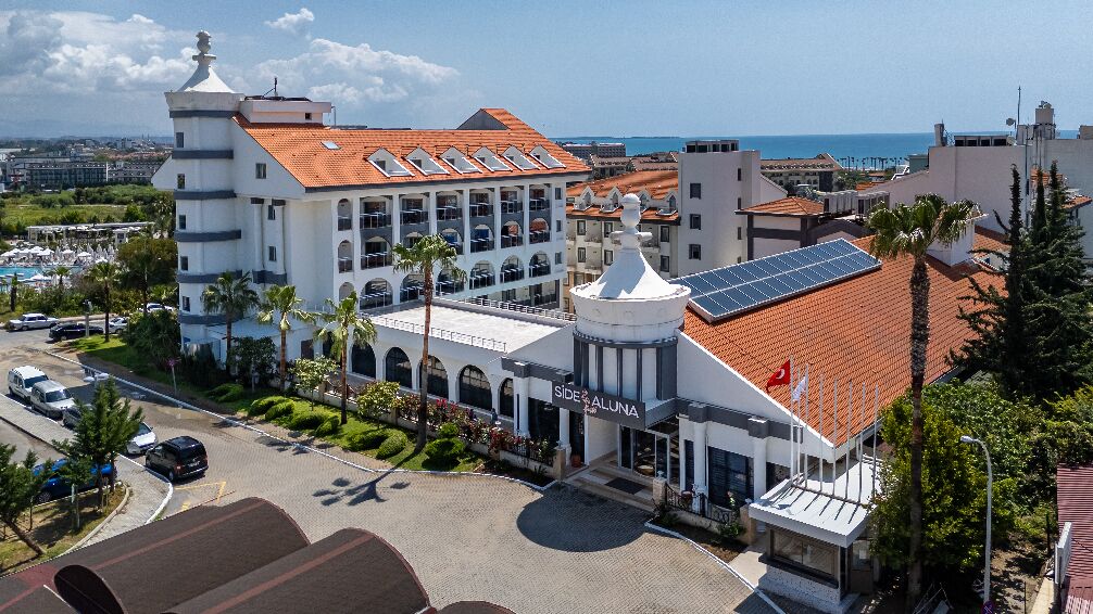 A hotel with a central courtyard, a pool, and a view of the sea.
