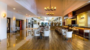 A spacious hotel lobby with a central bar area, multiple seating arrangements, and a polished wooden floor. - Side Aluna Hotel (Manavgat)