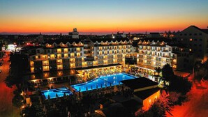 A hotel with multiple balconies, a central pool area, and a sunset view. - Side Aluna Hotel (Manavgat)