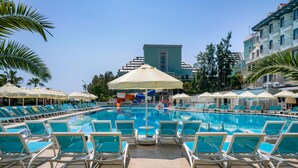 A pool area with lounge chairs and umbrellas, surrounded by buildings. - Side Aluna Hotel (Manavgat)