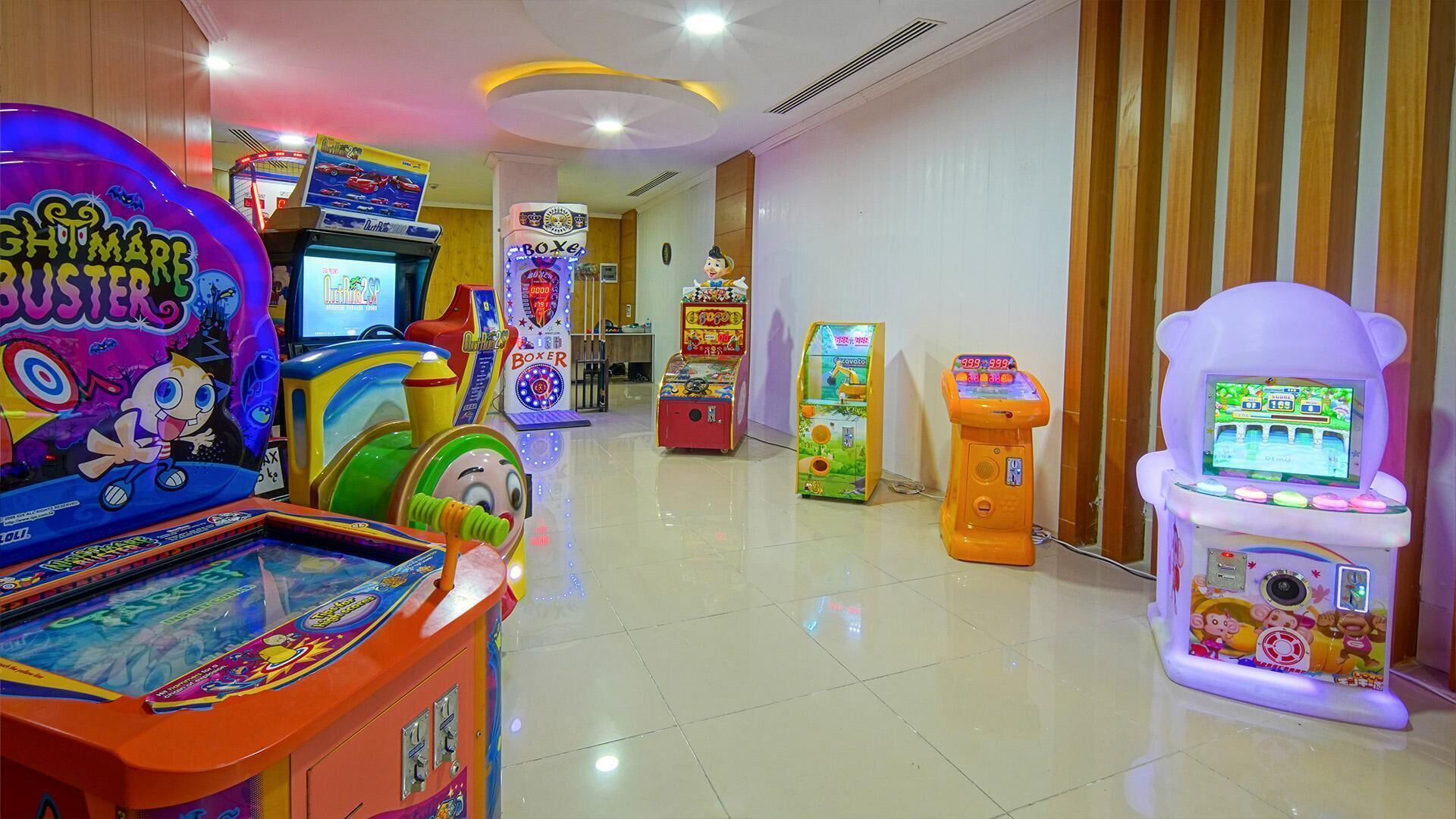 Zona luminosa de una sala de juegos con varias máquinas, incluyendo un juego 'Boxer' y un juego 'Doom'.