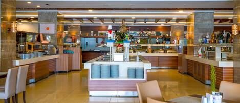 A modern hotel lobby with a central counter, seating areas, and a decorative plant.