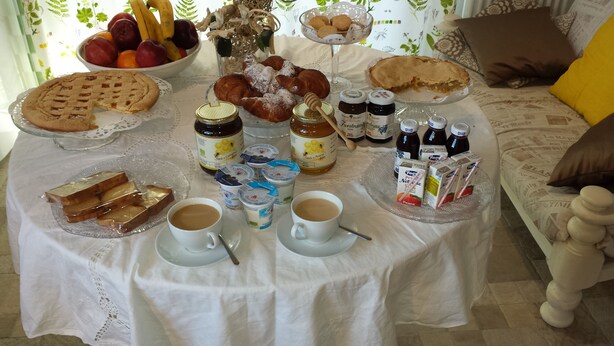 Ein Frühstückstisch mit Gebäck, Früchten, Honig, Marmeladen und Getränken.