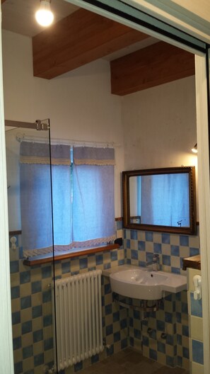A bathroom with a checkered tile backsplash, a white sink, a mirror, and a window with curtains. - B&B Cadrecca Tra Terra Luna e Mare (Licciana Nardi)