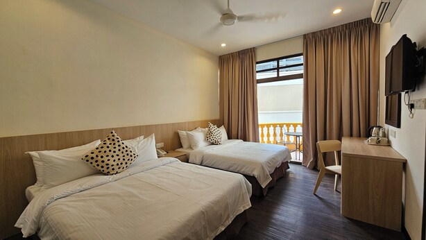 A hotel room with two beds, a desk, a chair, a television, and a balcony with curtains. - HOTEL 22 GURNEY (George Town)