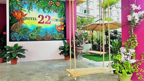 A colorful mural with the text "HOTEL 22 GURNEY" and a swing set with a hanging chair and umbrella. - HOTEL 22 GURNEY (George Town)