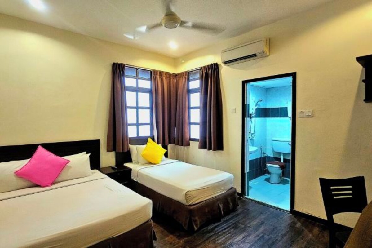 A hotel room with two beds, a ceiling fan, an air conditioning unit, and a view of the bathroom through a door.