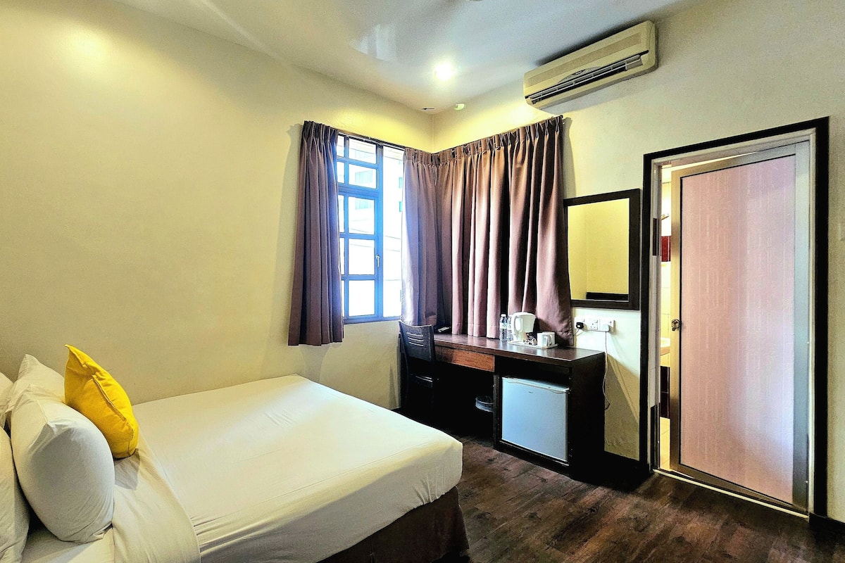 A hotel room with a bed, a desk, a mirror, and a wardrobe.