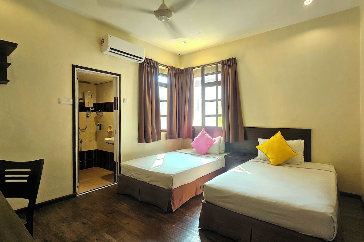 A hotel room with two beds, a bathroom, and a small seating area.