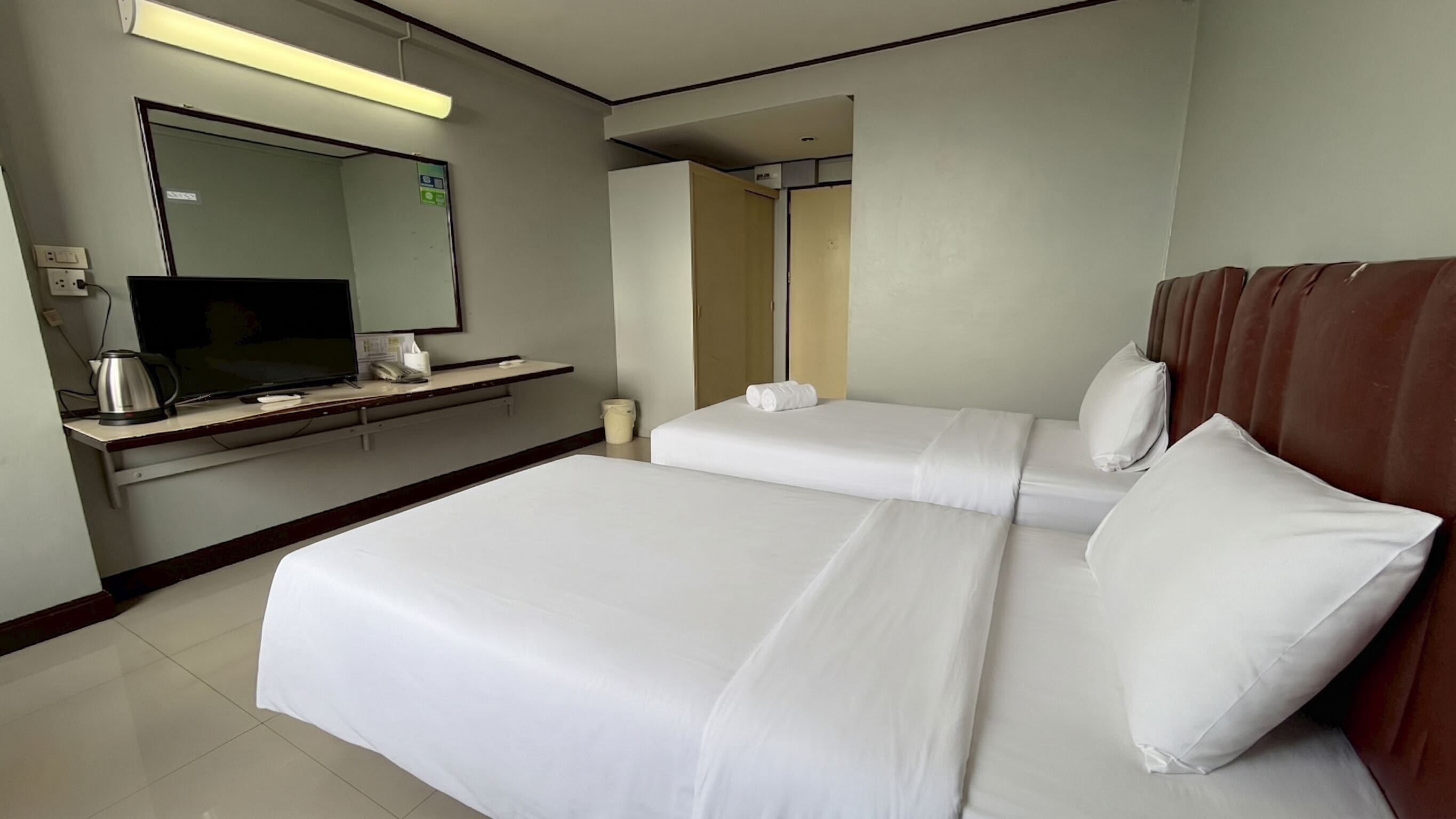 A hotel room with a bed, a television, a coffee maker, and a mirror.