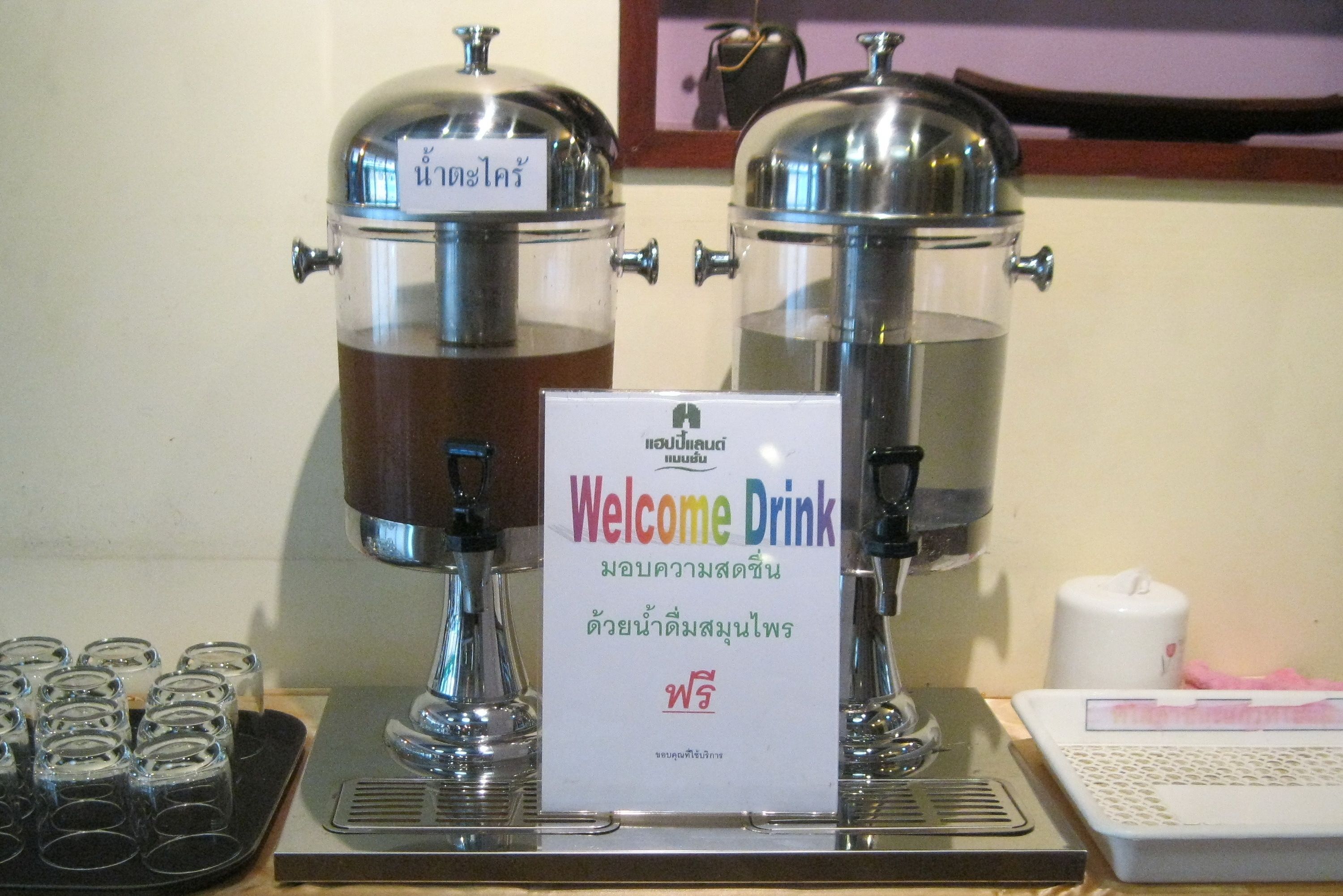 Una estación de café con dos dispensadores y un letrero que dice 'Welcome Drink'.