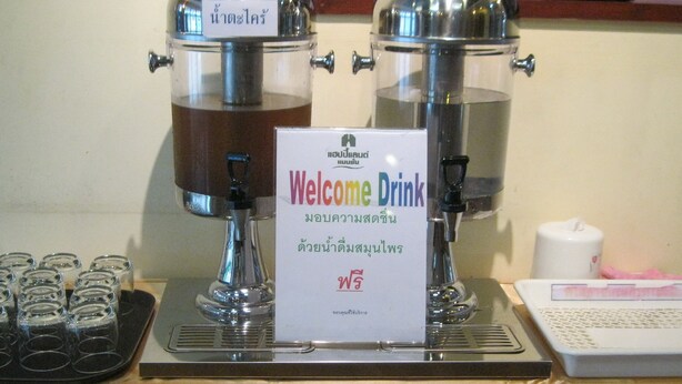 A coffee station with two coffee dispensers and a sign that reads "Welcome Drink". - Happyland Mansion (Bangkok)