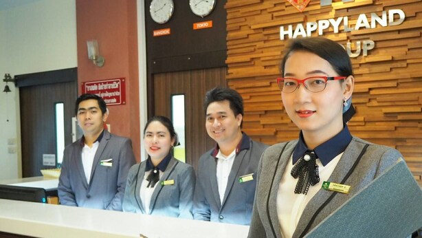 A reception desk with a wooden panel wall and clocks indicating time in Bangkok and Tokyo. - Happyland Mansion (Bangkok)