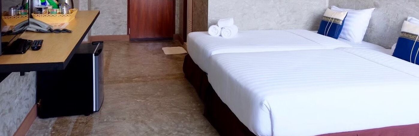 A hotel room with a bed, a desk with a telephone, and a small trash bin.