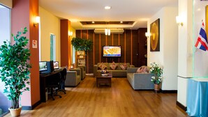 A hotel lobby with a reception desk, seating area, and a television screen. - Happyland Mansion (Bangkok)