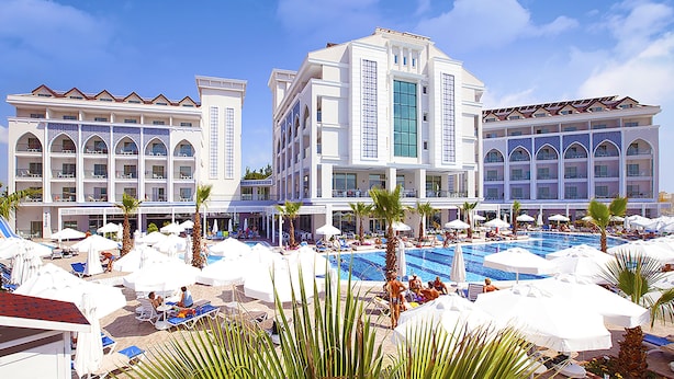 A hotel with multiple balconies, a swimming pool, and sun loungers. - Diamond Elite Hotel & Spa - Adults Only (Manavgat)