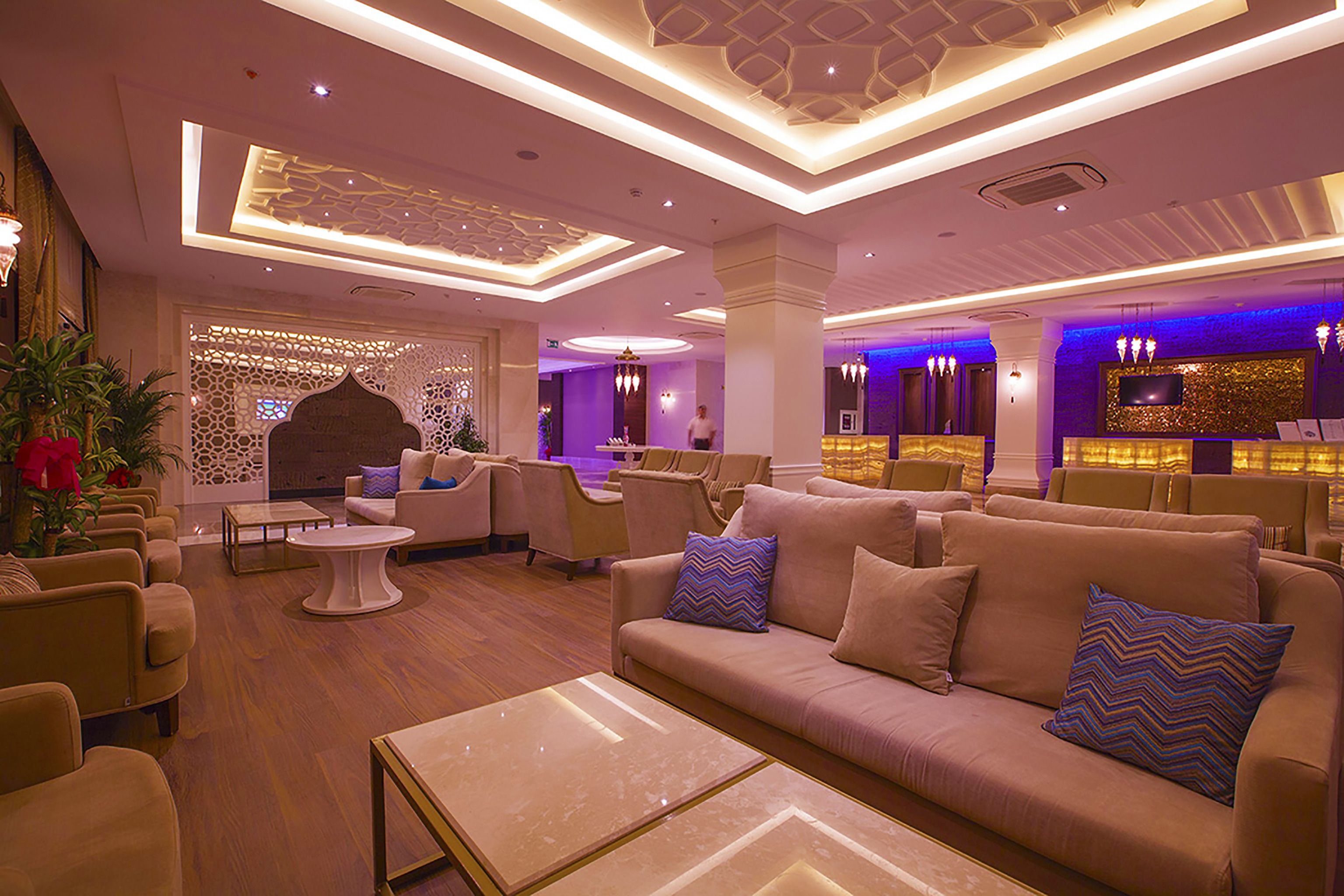 A spacious lobby with a modern design, featuring sofas, armchairs, and a reception desk.