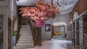 Un'imponente scalinata con un'installazione floreale sopra, pareti in marmo e un'area reception moderna.