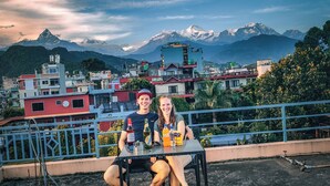 A couple sitting at a table with a mountain view in the background. - Nanohana Lodge (Pokhara)