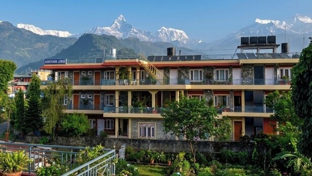 A hotel with multiple floors, balconies, and a view of snow-capped mountains. - Nanohana Lodge (Pokhara)