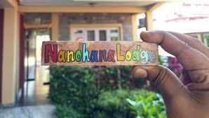 A hand holding a sign with the text "Nanohana Lodge". - Nanohana Lodge (Pokhara)