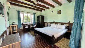 A bedroom with a large bed, a wooden desk, a chair, and a wardrobe. - Nanohana Lodge (Pokhara)