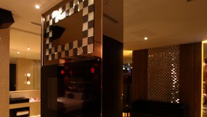 En modern hotellobby med ett väggmönster i rutmönster, en sittgrupp med en soffa och ett soffbord samt en synlig receptionsdisk.
