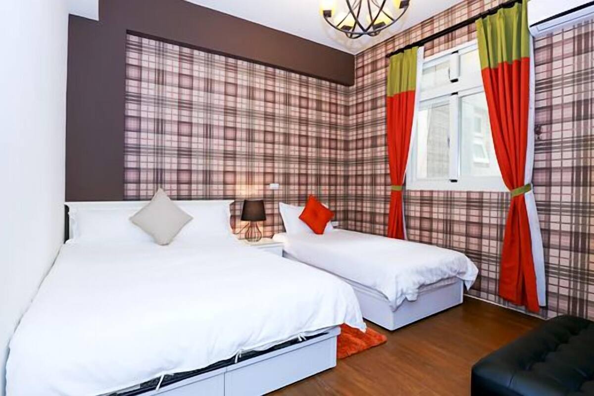 A double room with two beds, a nightstand, a lamp, and a window with curtains.