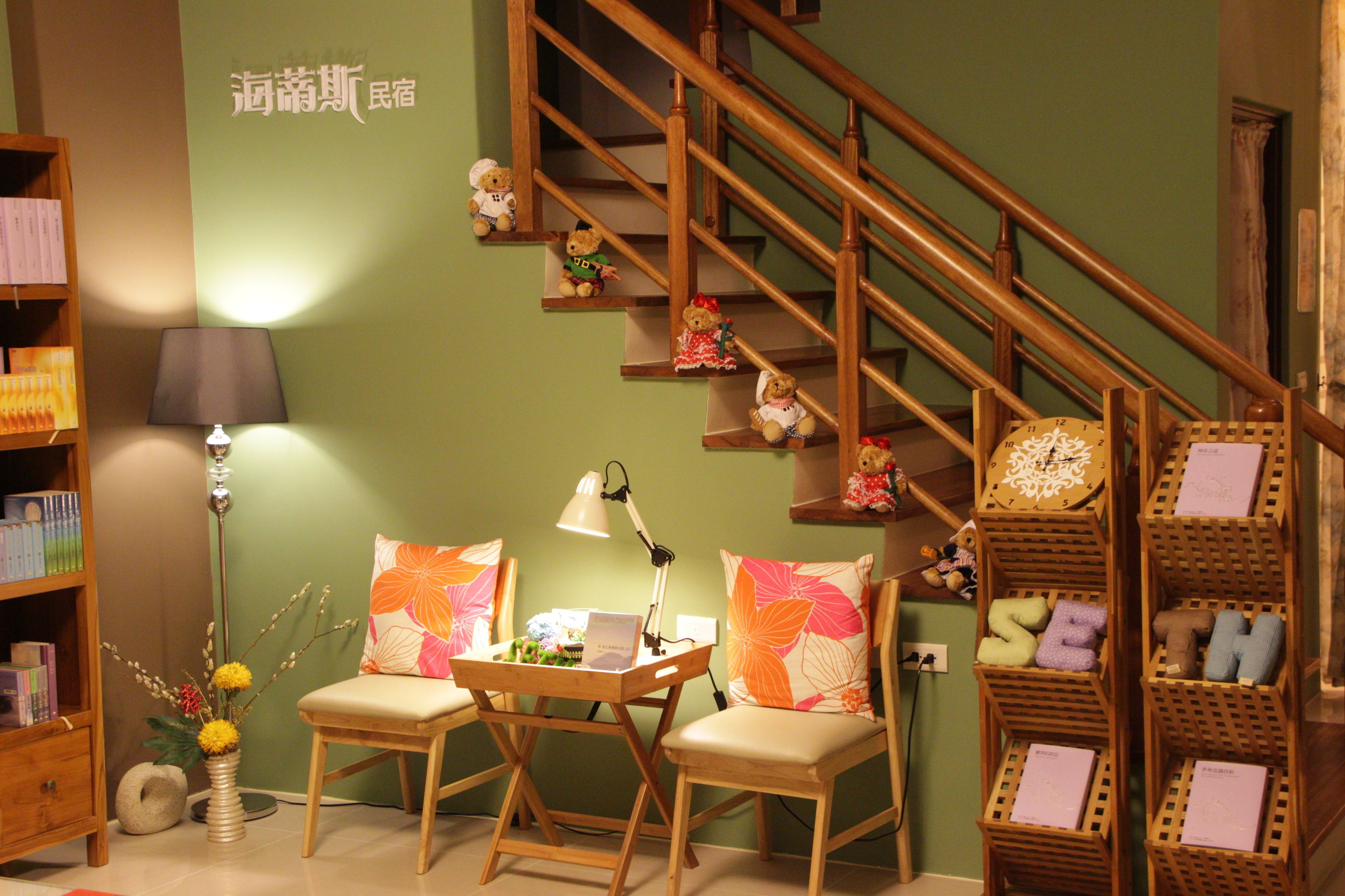 Ein gemütliches Zimmer mit einer Holztreppe, einem Schreibtisch mit Lampe, zwei Stühlen, einem Bücherregal und einer Wand mit Dekoration.