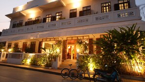 A two-story building with a balcony, potted plants, and a bicycle parked in front. - Baan Samsa (Luang Prabang)