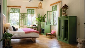 A room with a bed, a desk, a chair, a green cabinet, and a potted plant. - Baan Samsa (Luang Prabang)