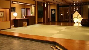 A traditional Japanese interior with tatami flooring, a reception desk, and a decorative paper lantern. - Yunoyado Saika (Yurihama)