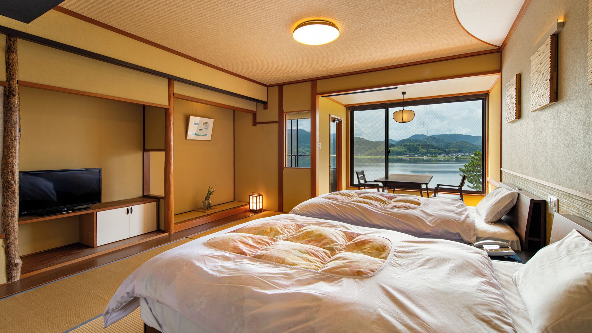 Una camera d'albergo con un letto, una TV, una scrivania e vista su un lago.