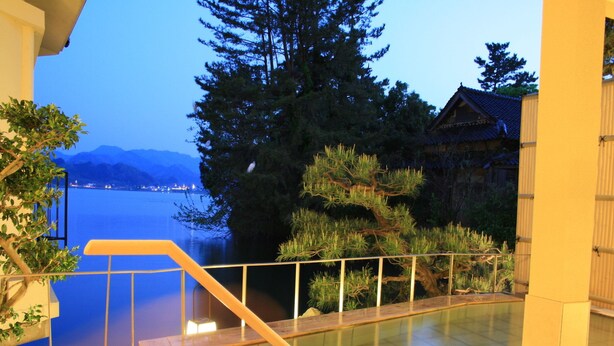 A terrace with a view of a lake and mountains, a wooden staircase, and a railing. - Yunoyado Saika (Yurihama)