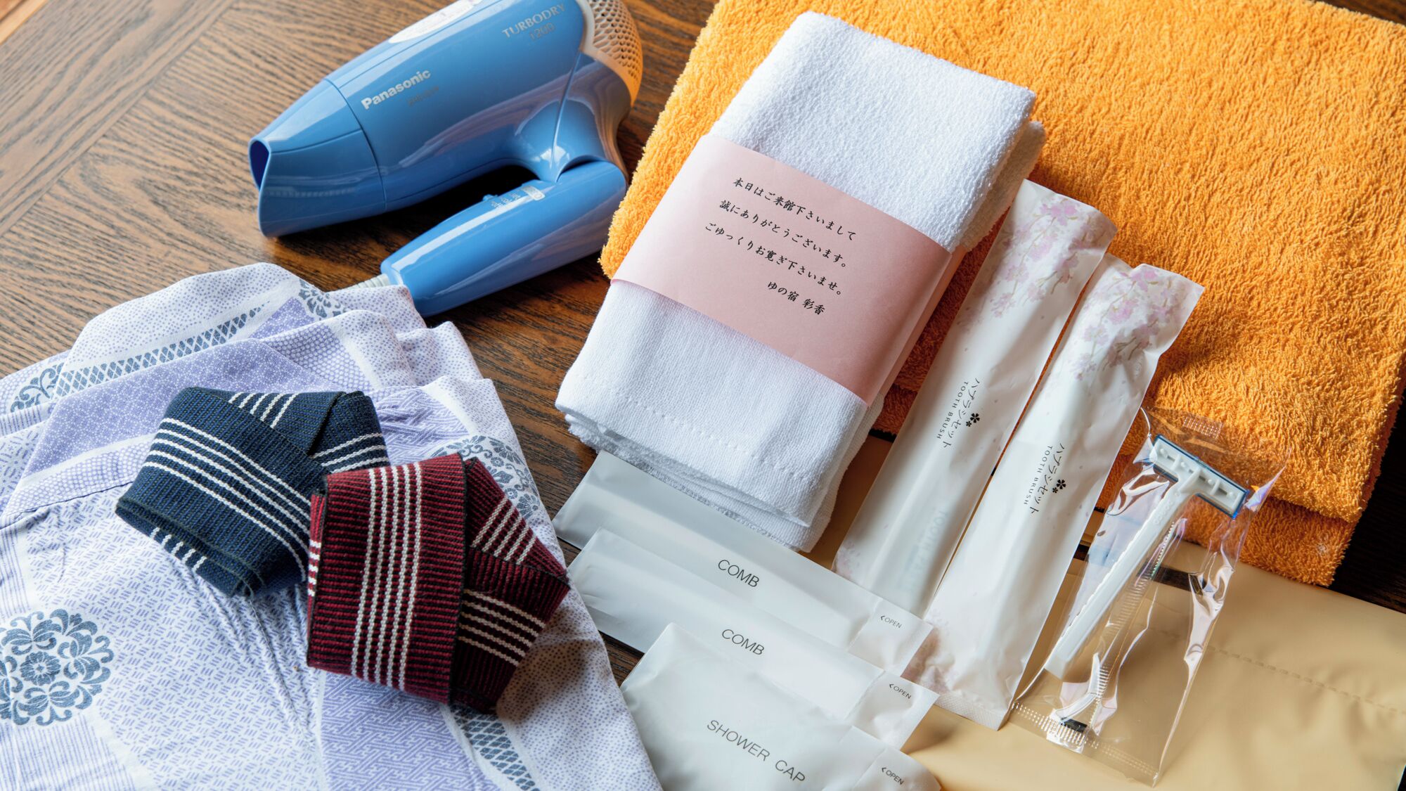 Un bagno con un asciugacapelli blu, asciugamani, un tappetino da bagno rosa e cappucci per la doccia.