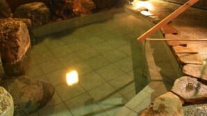 A hot spring area with a wooden deck and large rocks. - Yunoyado Saika (Yurihama)