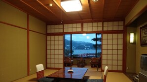 A traditional Japanese room with tatami flooring, a low table, and a view of a lake and mountains. - Yunoyado Saika (Yurihama)