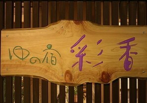 Un letrero de madera con caracteres japoneses y una figura verde.