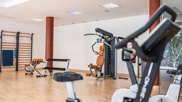 A gym with exercise equipment, a wooden floor, and a large window.