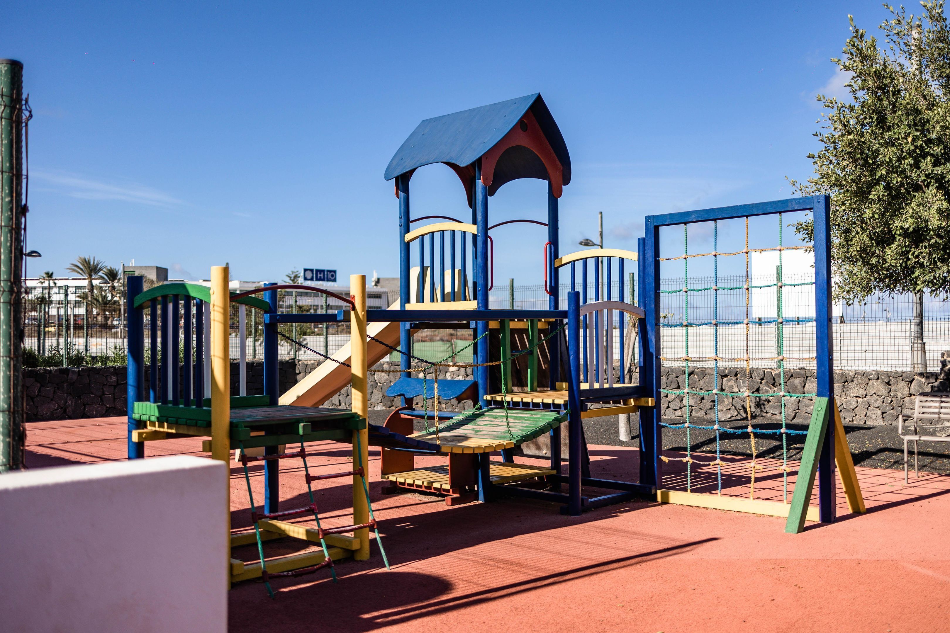 Un parque infantil con estructuras para escalar y un tobogán.