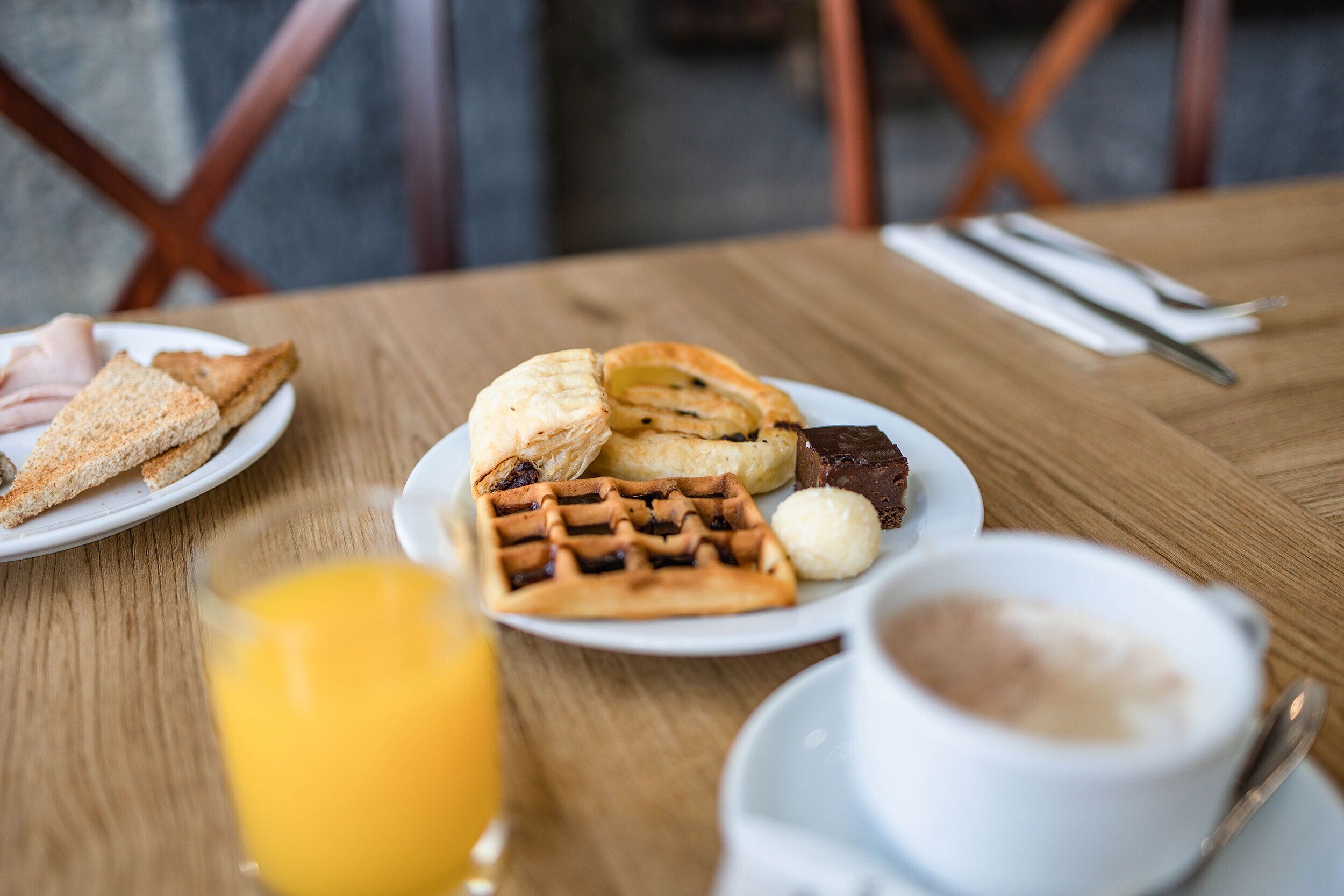 Une table de petit-déjeuner avec des gaufres, des viennoiseries et une tasse de café.