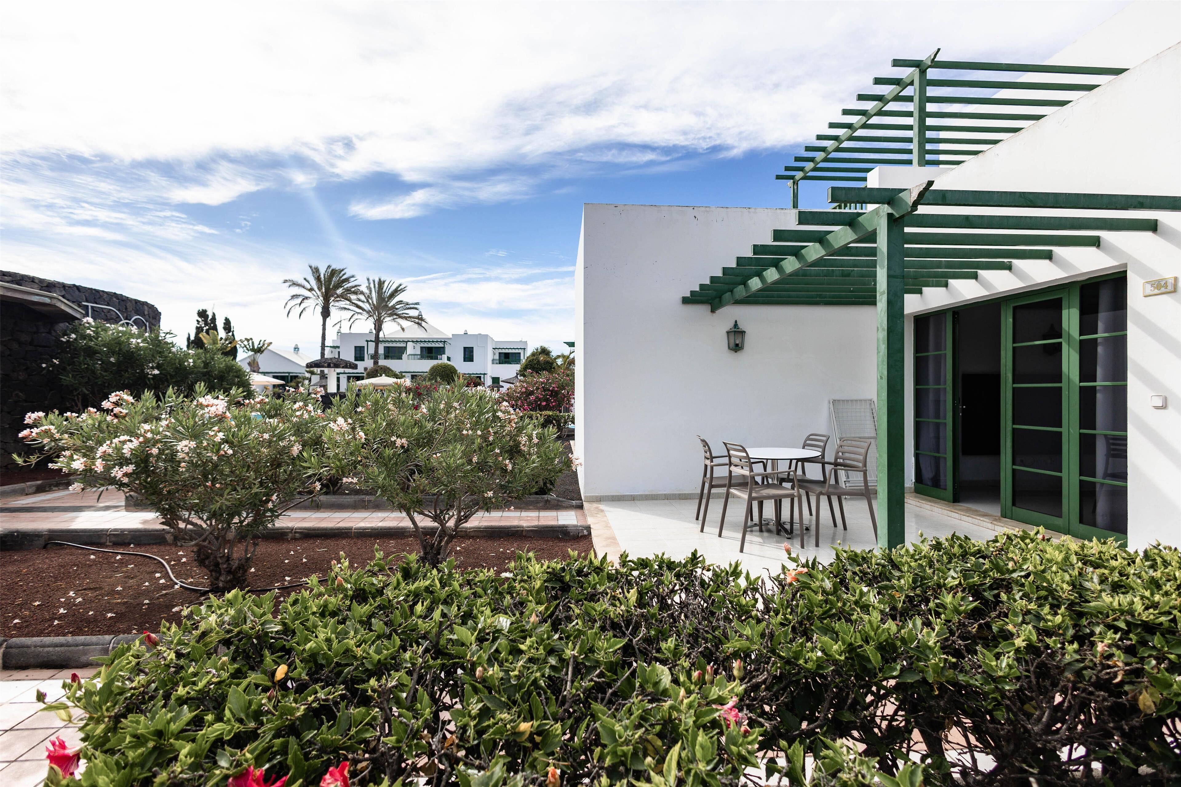 Un bâtiment moderne à l’extérieur blanc, doté d’un escalier vert et d’un patio aménagé avec du mobilier d’extérieur.