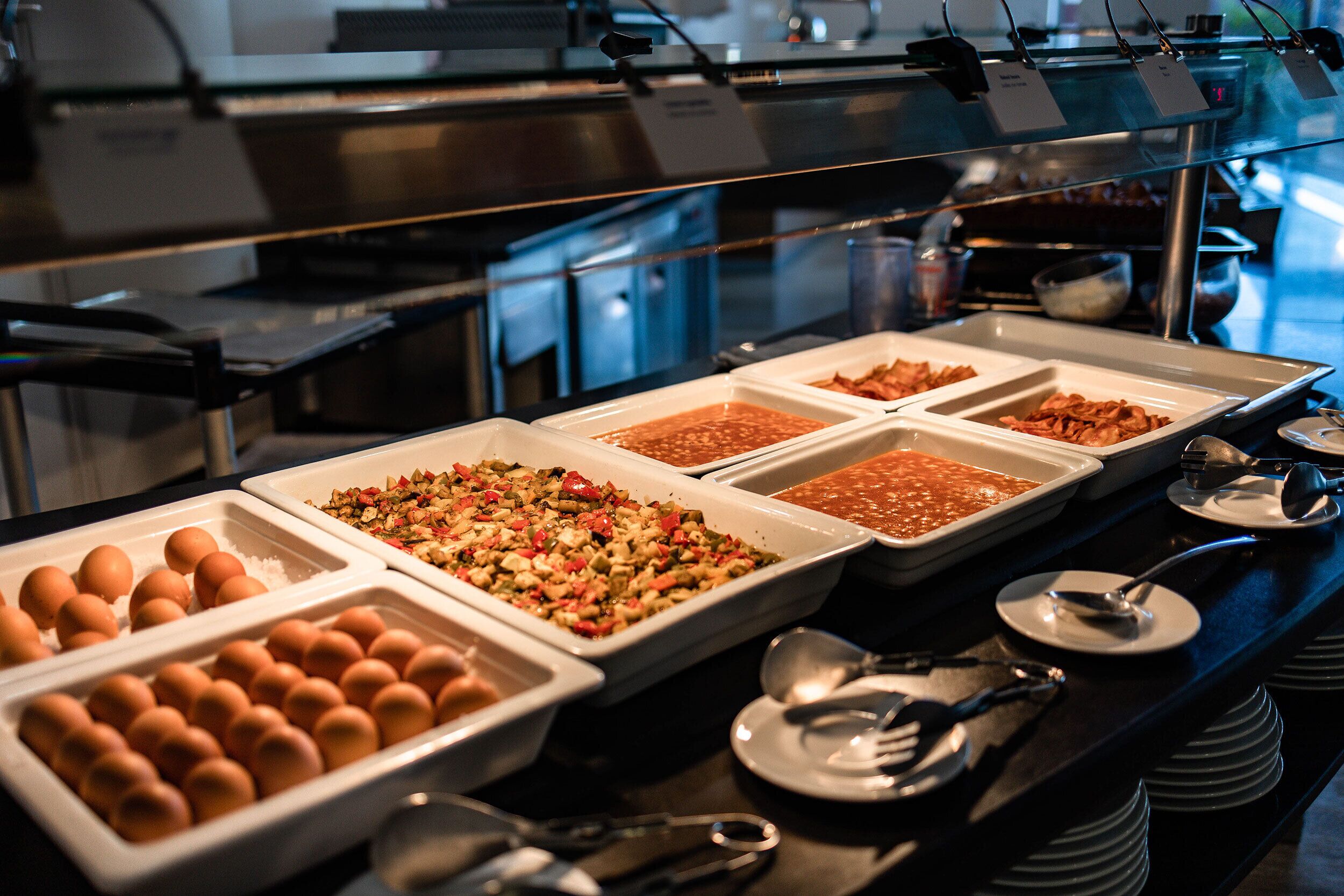 Un buffet proposant une variété de plats, notamment des œufs, des légumes et des sauces.