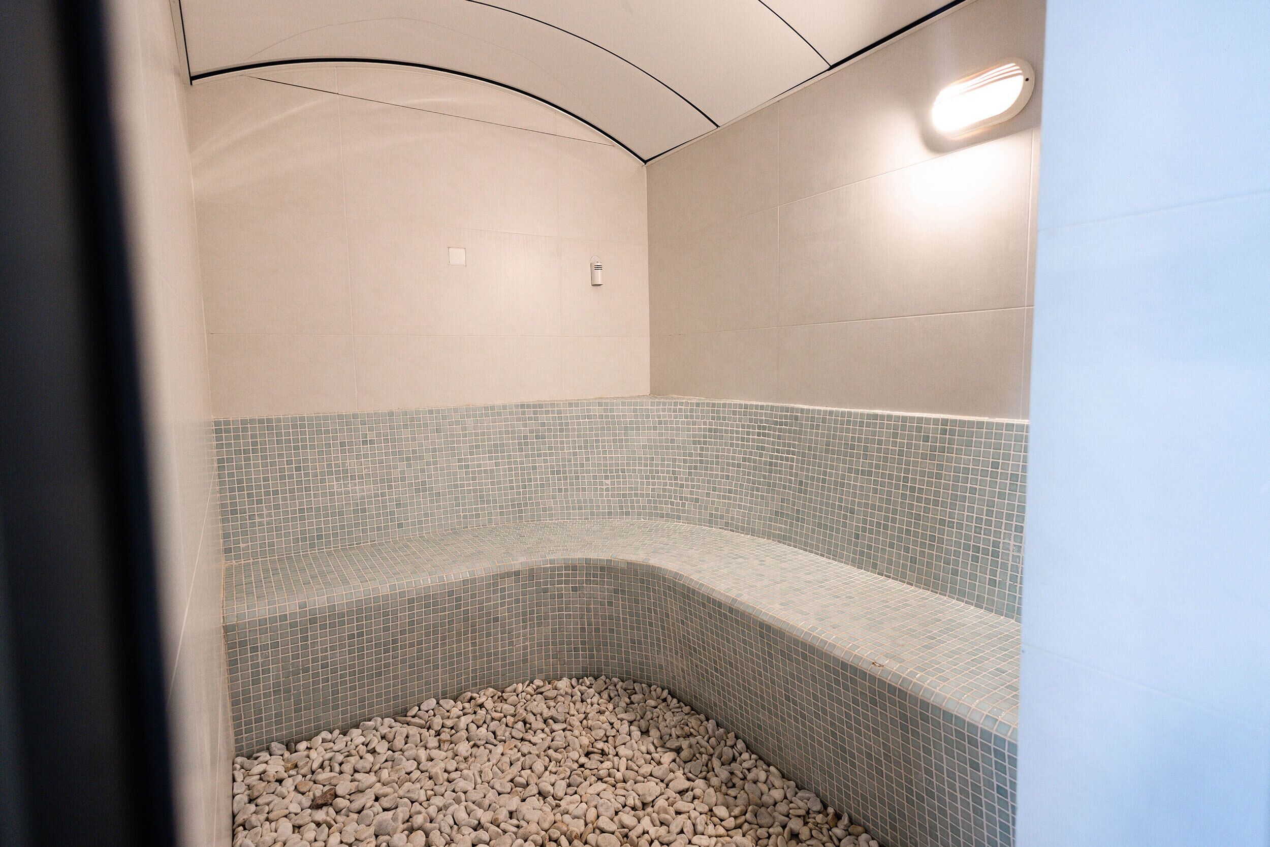 A spa area with a curved seating area and a pebble-filled basin.